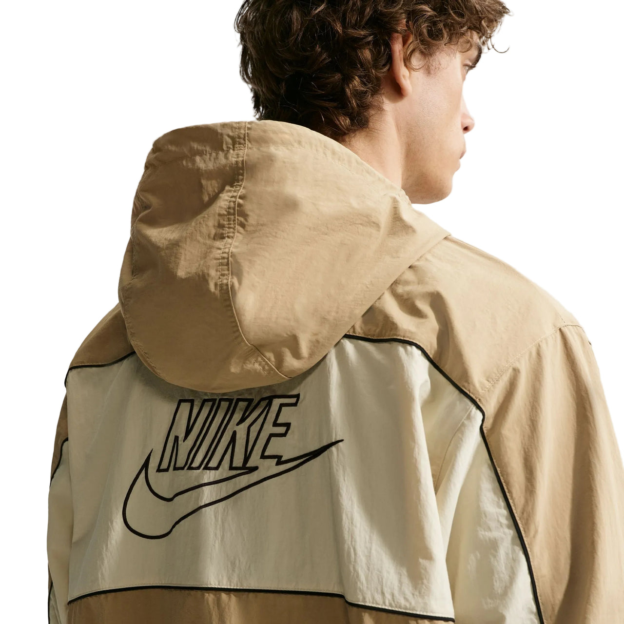 Person wearing a beige Nike jacket on a white background