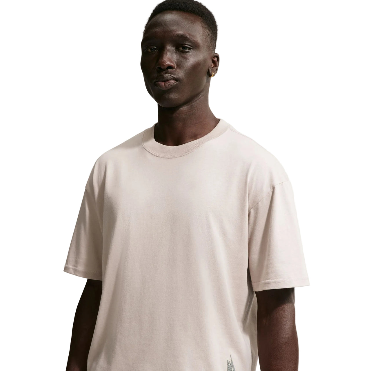 Man wearing a plain Nike beige t-shirt against a white background