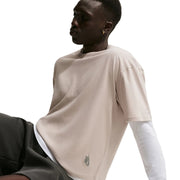Person wearing a beige Nike T-shirt with a small logo on a light background