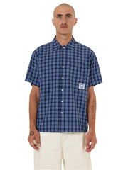 Man wearing a blue checkered shirt with a logo on a white background