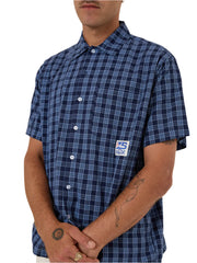 Person wearing a blue plaid shirt with a logo on a white background