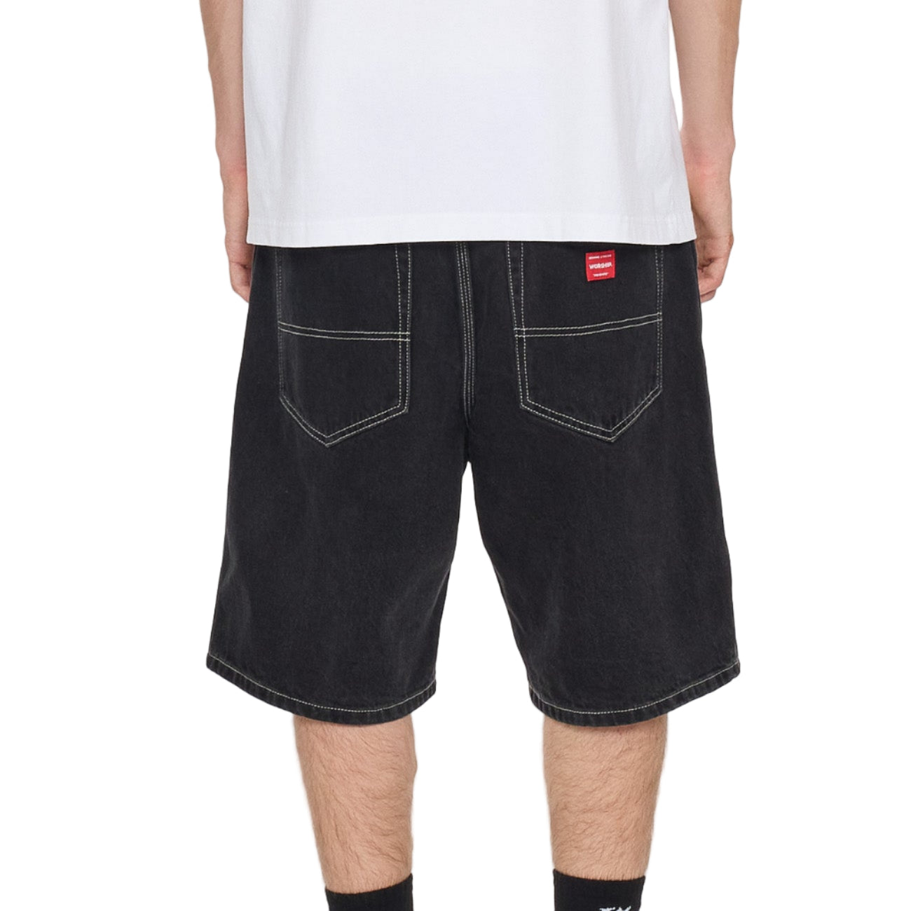 Person wearing black denim shorts with a visible brand logo on a white background